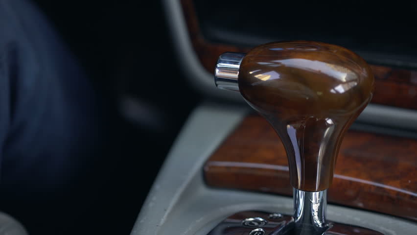 Man shifting gear, automatic transmission, luxury car with wooden interior