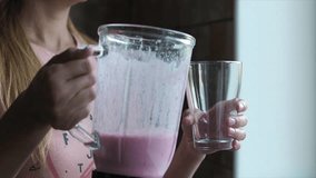 Young woman pouring tasty raspberry smoothie into glass, slow motion video