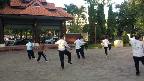 Chiang Mai, Thailand - July 1st 2018: Tai chi morning practice in Buak Haat Public park. Male and female elders training. Outdoor sport activities. Group of thai people practice traditional taijiquan.