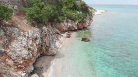 Aerial drone view of a rocky cliffs, wild beach  and clear sea with turquoise , emerald clear waters 