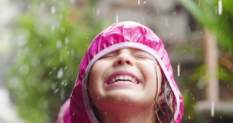 A happy girl is playing in the rain and is happy because she has fun. He opens his arms as a sign of freedom and love for nature.
