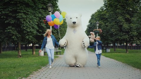 Mom and daughter and a polar bear are having fun along the street. Children's holiday concept