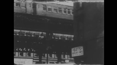 1940s: L train rolls across elevated track in city. Woman smokes cigarette in open apartment window. Man holds hands with children and walks down sidewalk.