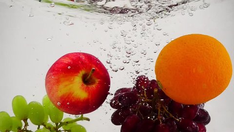 Apple, orange and grapes falling into water with bubbles in slow motion. Fruit on white background. – Video có sẵn