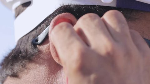 Industrial workers puts on his ear plugs to protect them from extreme sound 