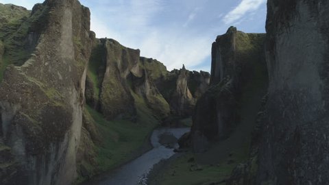 Fjadragljufur river canyon, steep rock walls, slow forward aerial shot, Iceland.
