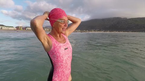 Senior woman preparing for early morning swim at the beach