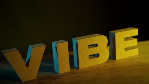Wooden VIBE letters in black background