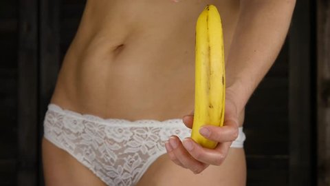 Young woman peeling banana in a white panties. 