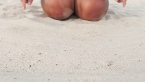 Woman drawing heart on sandy beach. Close up female fingers painting heart on sand on summer beach. Slow motion. Love concept