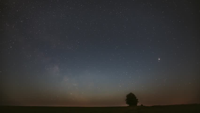 milky Way Galaxy In Night Starry Sky Above Lonely Tree In Summer Meadow. Glowing Stars And Meteorite Trails Above Landscape. View From Europe