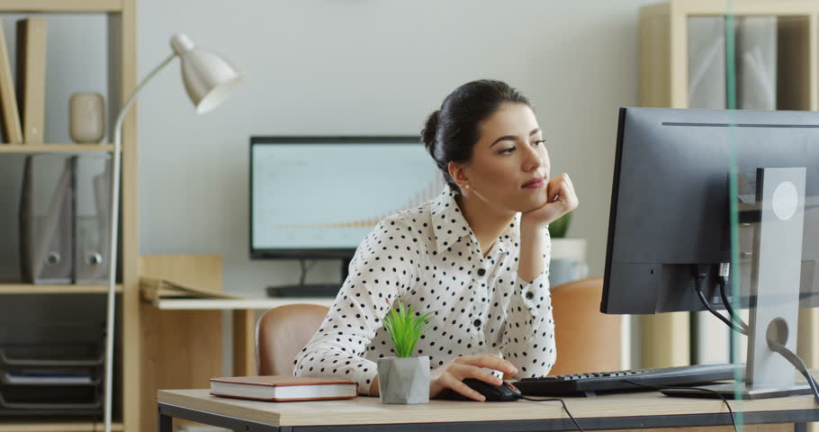 Pretty young relaxed woman working lazy at the laptop computer, then her boss coming and she working intensively. At the office. Inside.