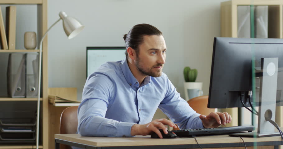 Young handsome man working at the laptop computer in the office, then his boss putting a lot of new work on the table. At office. Indoors.