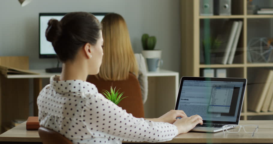 Back view of the Caucasian woman working on the laptop computer while it being attacked by virus and has error writing on the screen. Indoors.