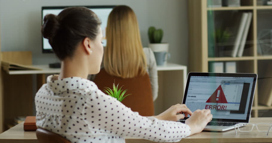 Rear of the female Caucasian office worker typing and texting on the laptop computer while it being broken and has error writing on the screen. Inside.