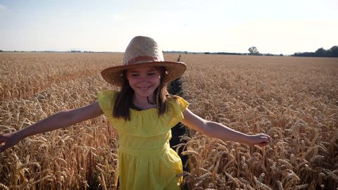 Happy childhood on nature kid girl yellow dress enjoy run for fun in a wheat field