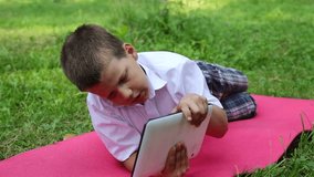 A boy is playing in a tablet in the park