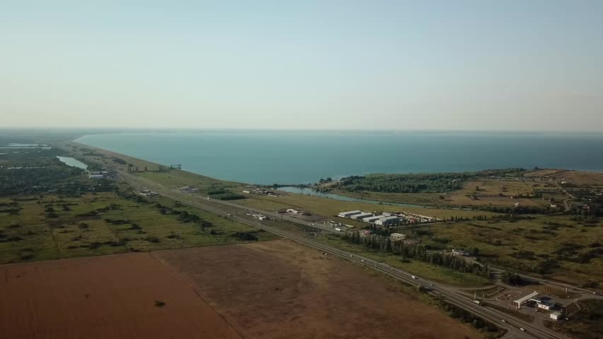 Summer aerial drone footage of transport junction, traffic cross road junction day view from above with green tree circle road, near is a wheat field. Top down view of traffic jam.