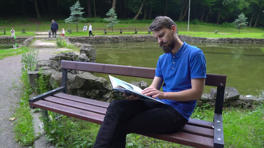 Cute boy is reading the book in the city park. 
