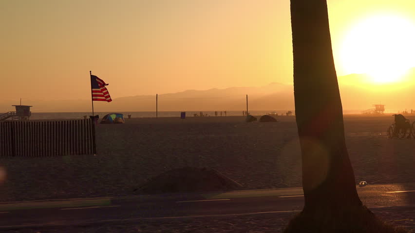 American flag blowing in the wind on the beach at sunset