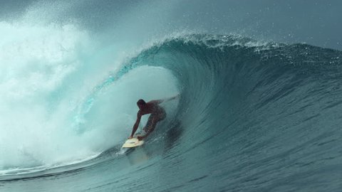 SLOW MOTION, CLOSE UP: Awesome male surfer rides a beautiful emerald barrel wave on a perfect day for surfing in sunny Tahiti. Young surfboarder enjoying catching perfect waves in French Polynesia.