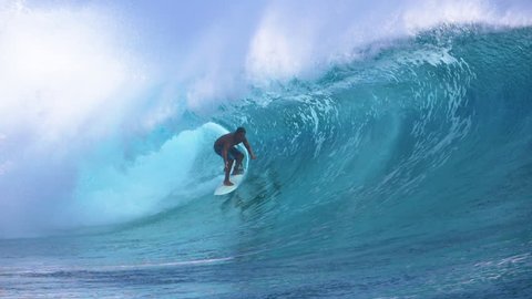 SLOW MOTION, CLOSE UP: Beautiful emerald tube wave curls behind extreme rider surfing in sunny French Polynesia. Awesome shot of pro surfboarder riding a big barrel wave splashing wildly behind him.