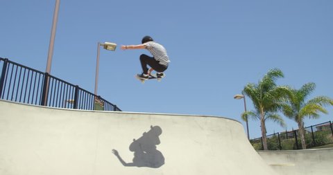 Skateboarder doing extreme air trick in skatepark on sunny day
