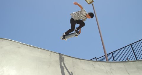 Slow motion skateboarder doing extreme air on vert ramp in skatepark
