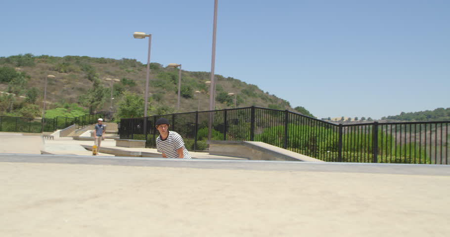 Slow motion man skateboarding doing extreme frontside air over hip in skatepark