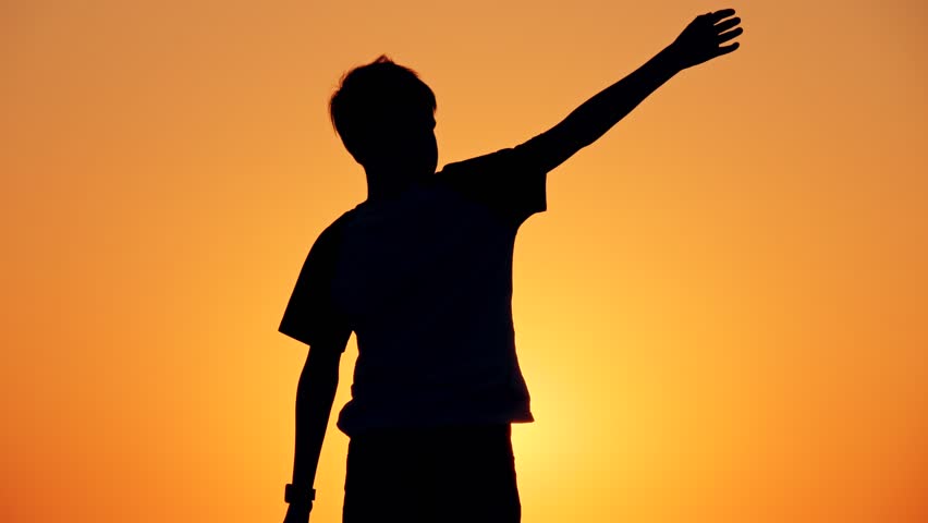 Silhouette of a boy standing on the beach, the concept of happiness, dream, human space, children