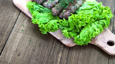 Fried meat in bacon on a wooden board with green lettuce leaves