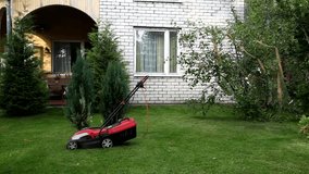 Tired lawn-mower is drinking beer near lawnmower. Summer garden, sunset. Funny, humor, humorous.
