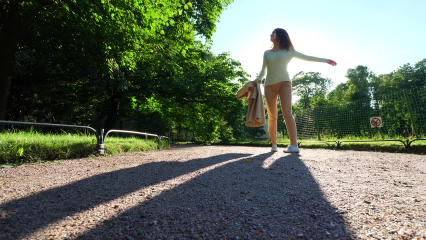 Happy girl dancing and fly around in sunshine in summer park