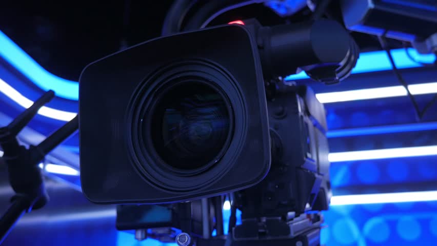 close-up view of tv camera on a crane, moving around in dark studio, illuminated decoration Royalty-Free Stock Footage #1013312636