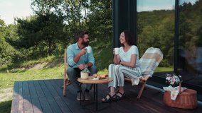 Beautiful caring young woman in trendy outfit serves coffee to a bearded man who actively uses laptop on the cozy terrace. Happy, family time, morning coffee. Couple goals, family portrait - Powered by Shutterstock - Get 15% off with code: PIKWIZARD15