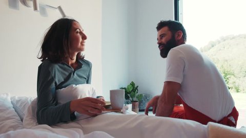 Romantic bearded man serves his beloved woman fresh croissant and hot coffee in the bed. Enjoying love, female dream, happy together. Anniversary, celebrating. Good morning.