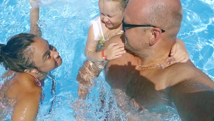 Father mother and cute little daughter swimming in the pool on a resort. | Shutterstock HD Video #1013314811