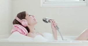 beauty woman wear headphone and sing song in bathtub