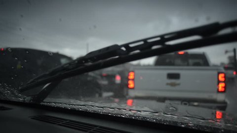 Windshield wipers work hard to clear water on a car stuck in traffic.