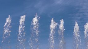 Tops of large fountain jets gushing upwards against blue sky