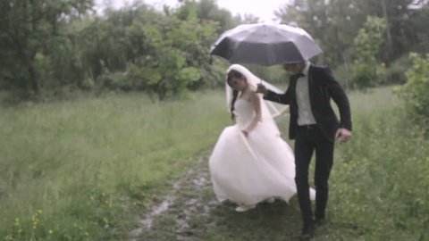 Happy and happy newlyweds with umbrella in the rain