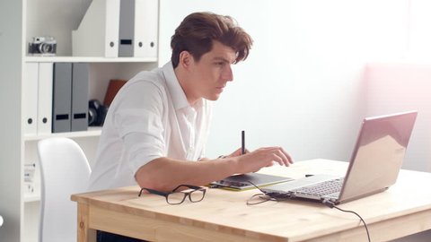 Casual male designer using graphics tablet in a bright office