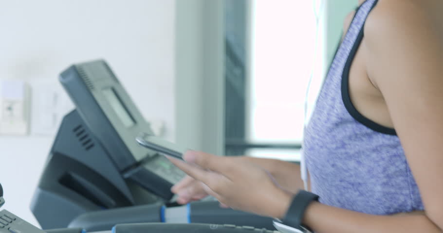 Asian girl running on the treadmill in the gym with earphones. | Shutterstock HD Video #1013340629