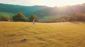 Yoga woman is jogging in summer sunny day around trees and mountains background under sun light with blue sky, Drone 4K Video