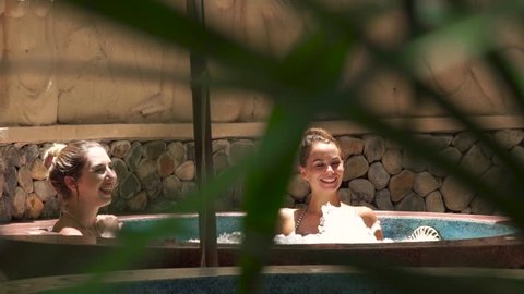 Happy woman taking jacuzzi bath in luxury spa center. Smiling woman relaxing and enjoying bathing in jacuzzi spa for body care. Skin care and body therapy. Beauty concept