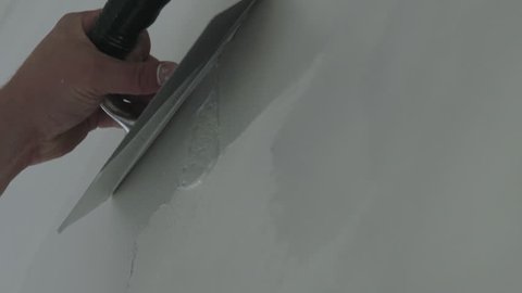 Slow motion handheld closeup worker applying decorative concrete plaster on the wall