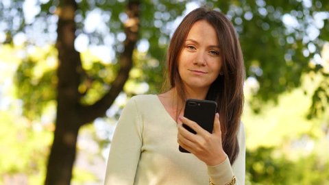 Smiling Woman browsing in smartphone, enjoy spending free time outside