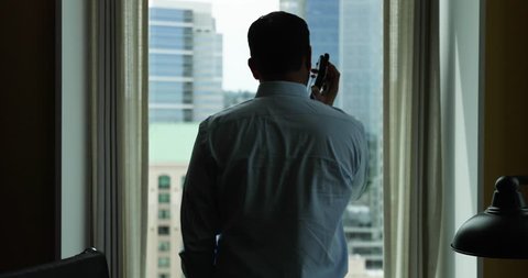 Businessman makes a phone call silhouetted by the city.