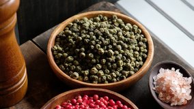 Close up panning clip of red and green peppercorns in wooden bowl.