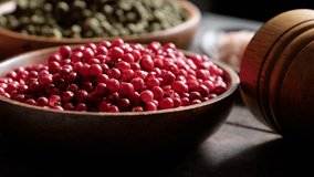Close up panning clip of red and green peppercorns in wooden bowl.